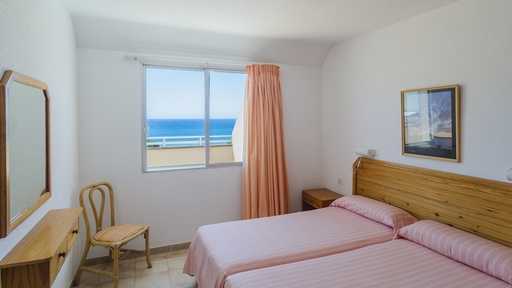 Habitación de los Apartamentos Durazno Sur con 2 camas, vistas al mar y mobiliario funcional